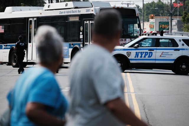 People walk by a crime scene as police search a car following a stand-off in front of the 45th Police Precinct in the Bronx on July 8th, 2021.